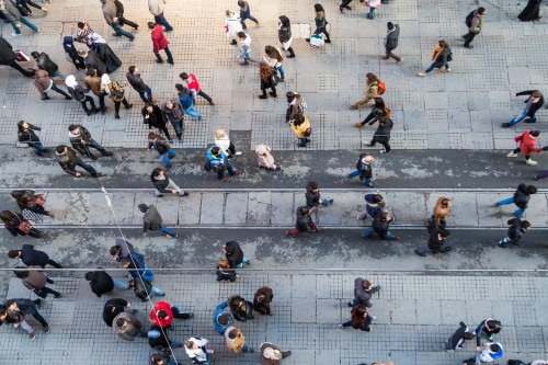 People walking along a busy pedestrian street viewed from above.