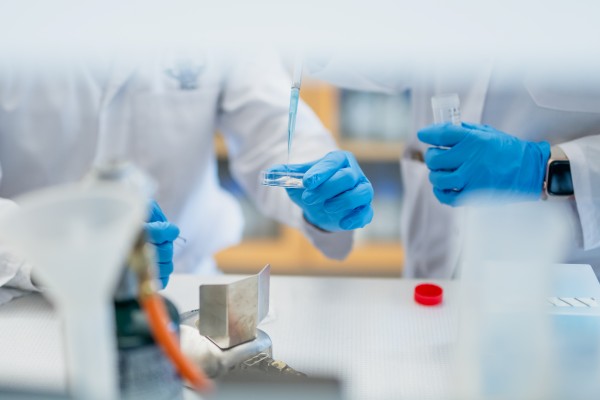 Laboratory researchers using a pipette and petri dish during a science experiment.