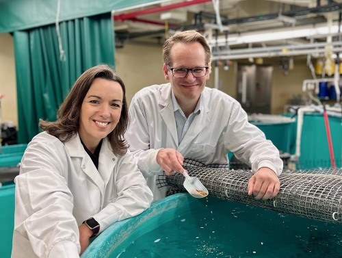 People in lab coats examining a tank in an aquaculture research facility.