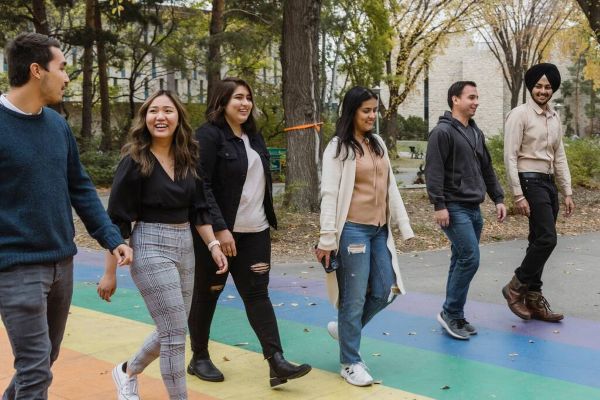 Group of students walking together along a colourful campus pathway outdoors.
